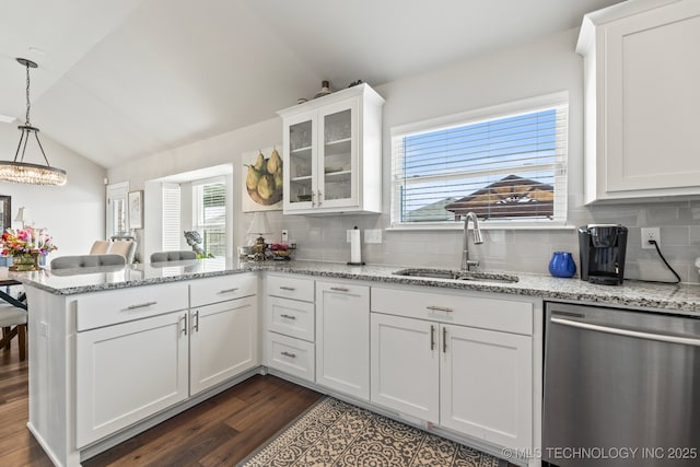 kitchen with a sink, dishwasher, dark wood finished floors, a peninsula, and lofted ceiling