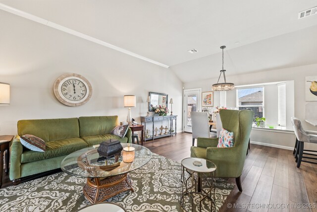 living room featuring visible vents, an inviting chandelier, lofted ceiling, wood finished floors, and baseboards