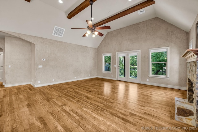 unfurnished living room featuring ceiling fan, visible vents, a stone fireplace, and high vaulted ceiling
