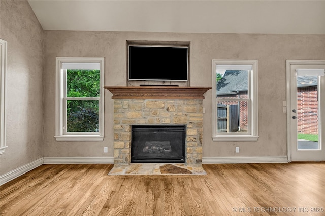 unfurnished living room featuring baseboards, wood finished floors, lofted ceiling, and a fireplace