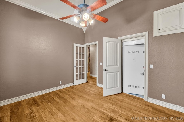 empty room with french doors, baseboards, a ceiling fan, and light wood-type flooring