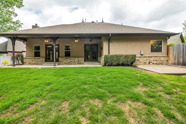 back of property with french doors, fence, stucco siding, and a yard