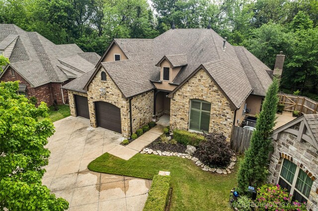 view of front of property featuring driveway, a garage, fence, a shingled roof, and stone siding