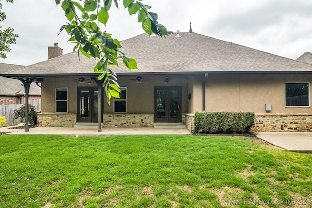 rear view of house featuring a yard, fence, french doors, and stucco siding