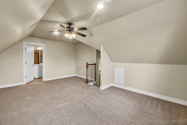 additional living space featuring a ceiling fan, visible vents, baseboards, lofted ceiling, and carpet