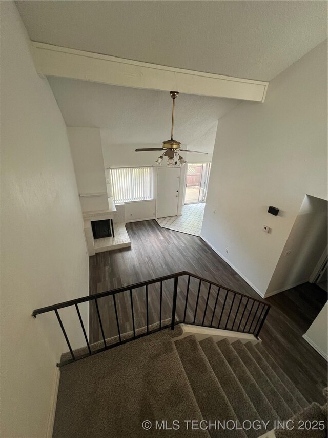 10911 E 11th Pl Unit 3B, Tulsa, OK 74128 - stairs featuring wood finished floors, a fireplace, beamed ceiling, baseboards, and ceiling fan