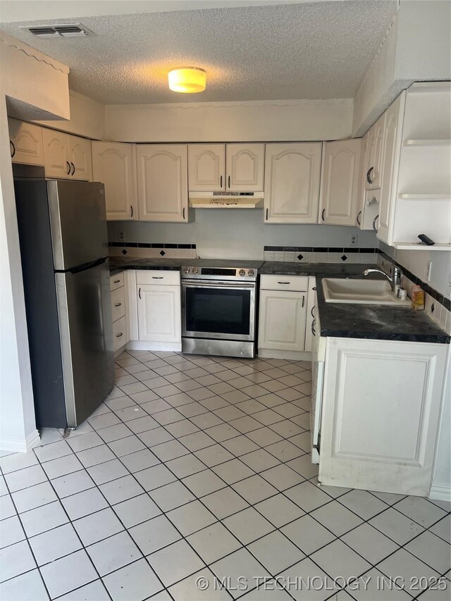 10911 E 11th Pl Unit 3B, Tulsa, OK 74128 - kitchen with dark countertops, a textured ceiling, under cabinet range hood, a sink, and stainless steel appliances