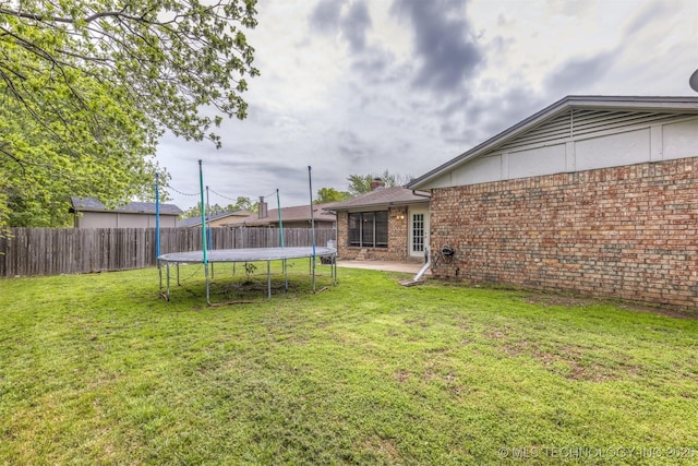 view of yard with fence private yard, a trampoline, and a patio