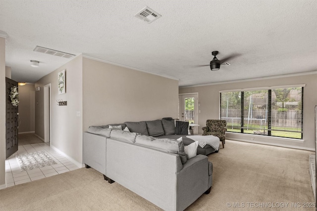 carpeted living area with visible vents, a ceiling fan, crown molding, and tile patterned flooring