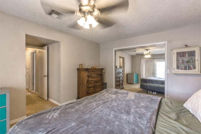 bedroom with visible vents, a ceiling fan, a textured ceiling, and light carpet