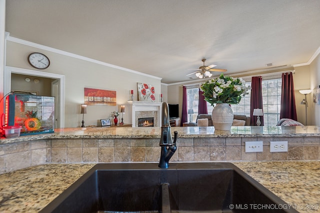 7408 E Forest Ridge Blvd, Broken Arrow, OK 74014 - kitchen with ceiling fan, crown molding, a sink, a warm lit fireplace, and open floor plan