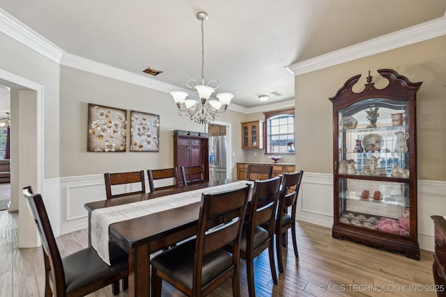 7408 E Forest Ridge Blvd, Broken Arrow, OK 74014 - dining space featuring crown molding, a notable chandelier, wainscoting, a decorative wall, and light wood-type flooring