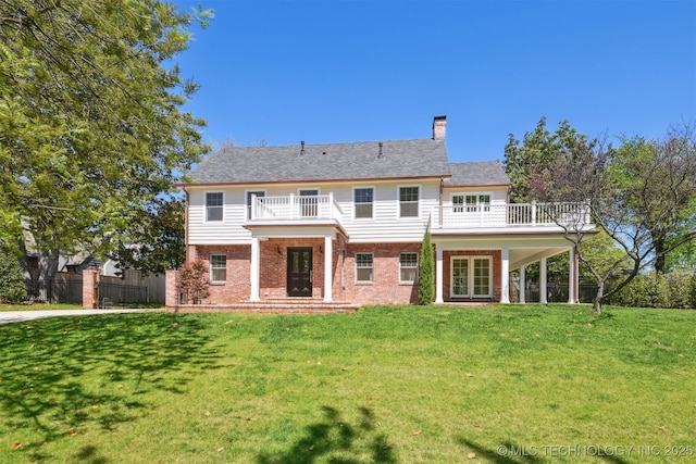 rear view of house with a chimney, french doors, a lawn, brick siding, and a balcony