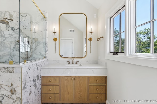 full bathroom with a marble finish shower, visible vents, vanity, and lofted ceiling