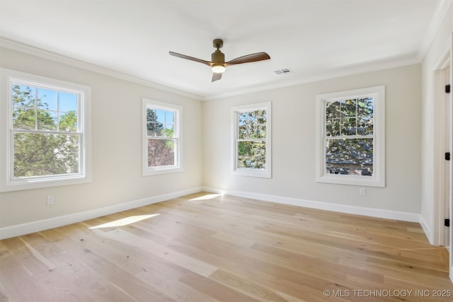 spare room featuring light wood-style floors, baseboards, ornamental molding, and a wealth of natural light