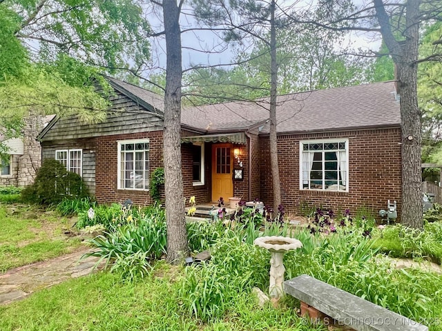 view of front facade with brick siding and a shingled roof