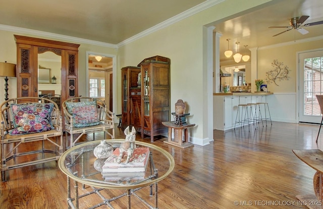 living area with crown molding, a ceiling fan, and wood finished floors