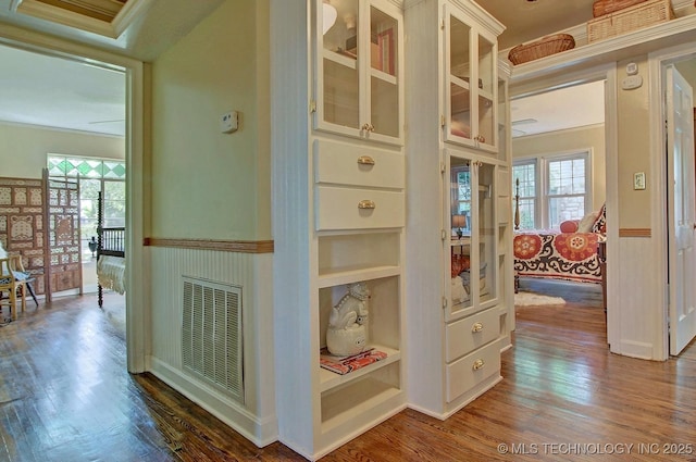 corridor featuring crown molding, visible vents, and wood finished floors