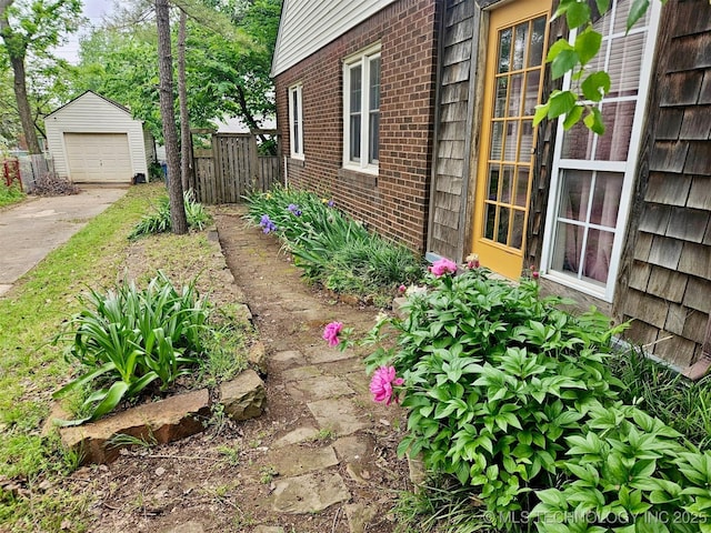 view of yard featuring concrete driveway, fence, an outbuilding, and a detached garage