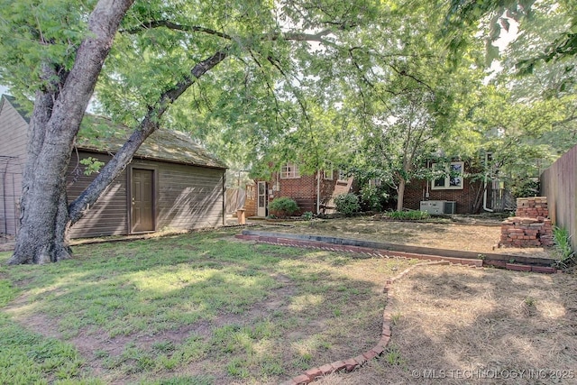 view of yard featuring fence, an outdoor structure, and central AC