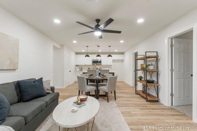 living room featuring light wood-style floors, baseboards, a ceiling fan, and recessed lighting