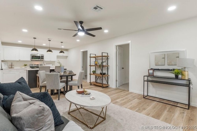 living area featuring visible vents, baseboards, ceiling fan, recessed lighting, and light wood finished floors