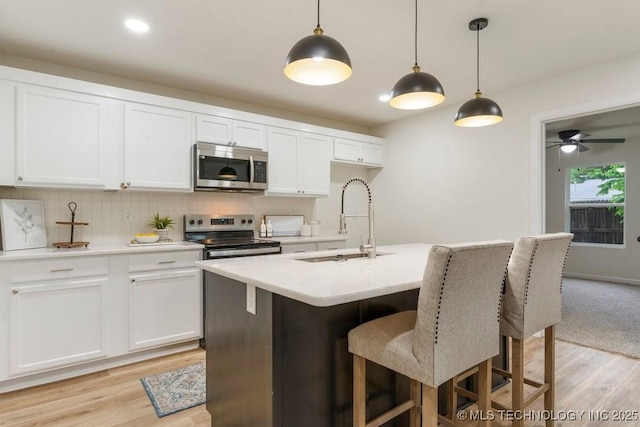 kitchen with decorative backsplash, a sink, light countertops, white cabinets, and stainless steel appliances