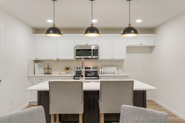 kitchen featuring light countertops, an island with sink, backsplash, and stainless steel appliances