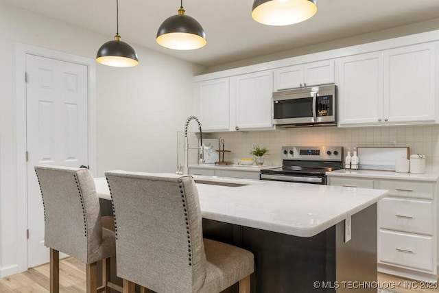 kitchen featuring decorative backsplash, a sink, appliances with stainless steel finishes, and white cabinetry