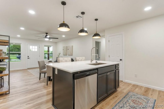 kitchen with decorative light fixtures, dishwasher, a sink, baseboards, and light countertops