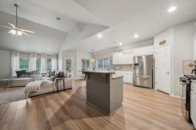 kitchen with visible vents, range with gas stovetop, open floor plan, ceiling fan, and stainless steel refrigerator with ice dispenser