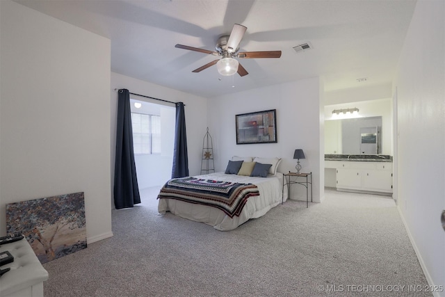 bedroom featuring visible vents, baseboards, ensuite bathroom, and light carpet