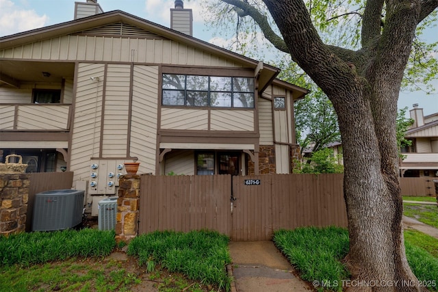 6371 S 80th Ave E Unit G, Tulsa, OK 74133 - view of property exterior featuring cooling unit, a chimney, a fenced front yard, and a gate
