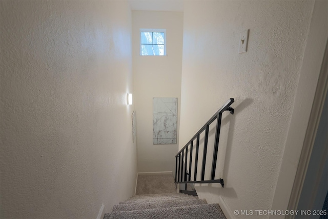 stairs featuring carpet flooring, a textured wall, and baseboards