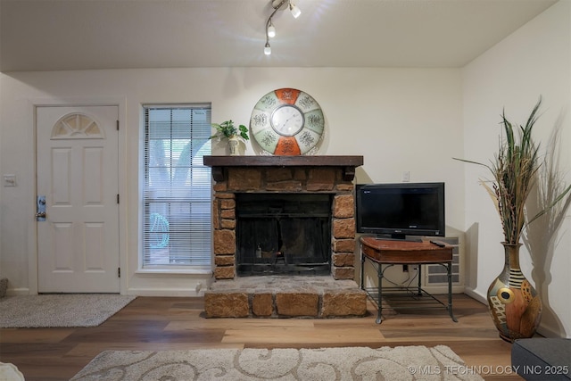 living area with a stone fireplace, baseboards, and wood finished floors
