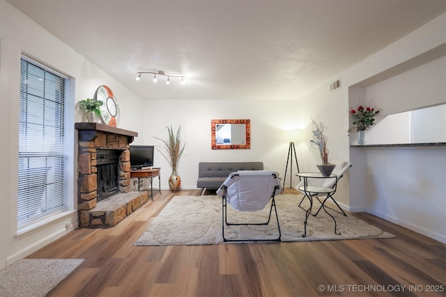 living room featuring baseboards, visible vents, wood finished floors, and a fireplace