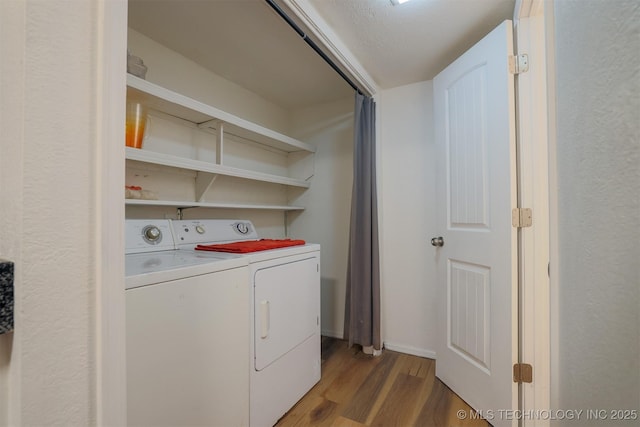 clothes washing area featuring wood finished floors, laundry area, and washing machine and dryer