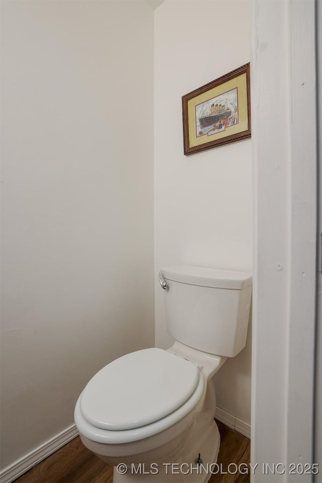 bathroom featuring baseboards, wood finished floors, and toilet