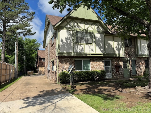 view of front facade with brick siding, fence, and driveway