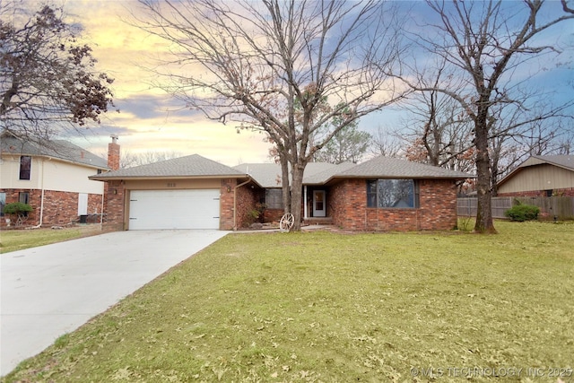 ranch-style home featuring brick siding, a garage, a lawn, and fence