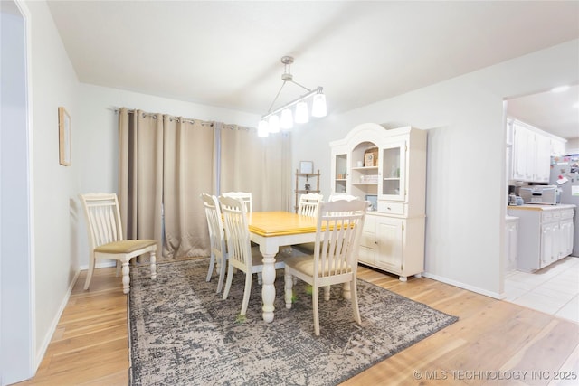 dining space featuring baseboards and light wood finished floors