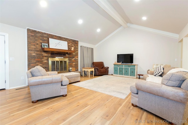 living area with vaulted ceiling with beams, light wood finished floors, a brick fireplace, and baseboards