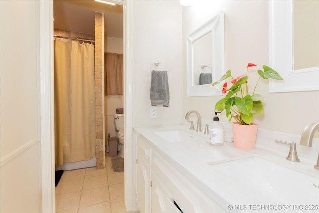 bathroom featuring toilet, double vanity, tile patterned floors, and a sink
