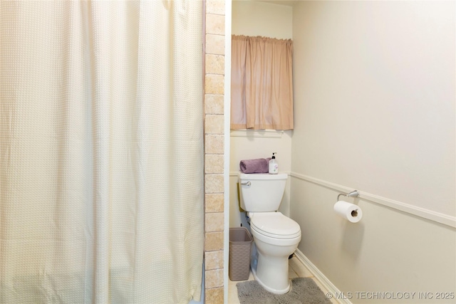 full bathroom featuring toilet, tile patterned floors, and a shower with curtain