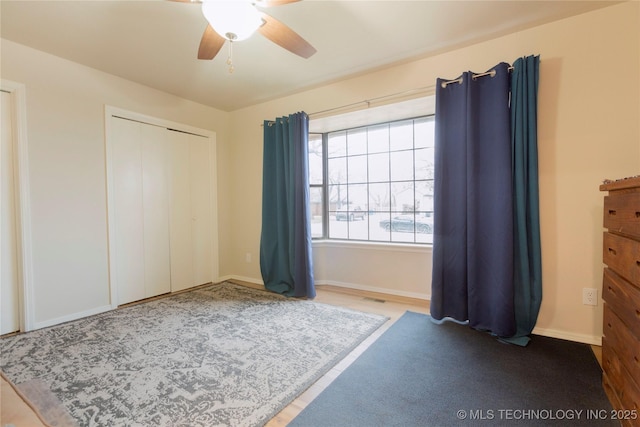 unfurnished bedroom featuring baseboards, visible vents, ceiling fan, and a closet