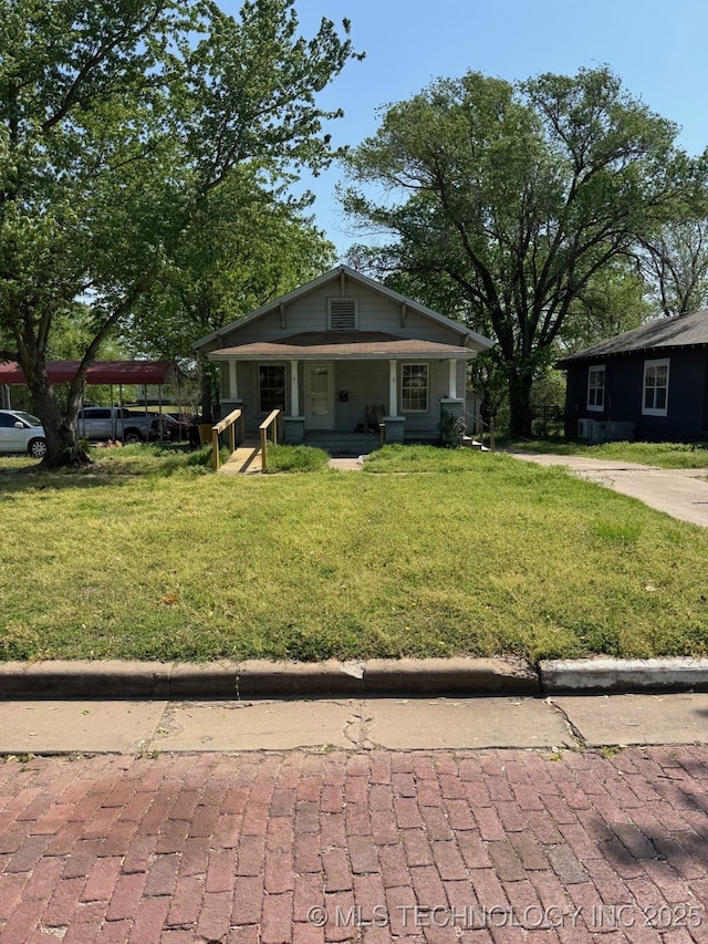 bungalow with covered porch and a front yard