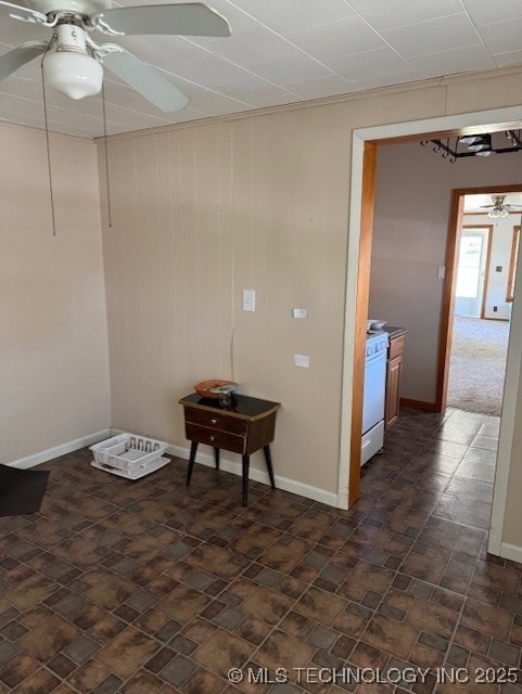 unfurnished room with baseboards, a ceiling fan, and wood walls