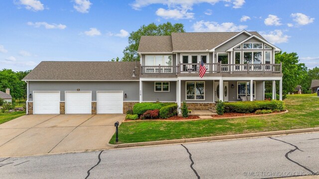 view of front of home featuring concrete driveway, stone siding, a front yard, and a garage