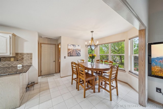 dining space featuring baseboards, light tile patterned floors, and an inviting chandelier