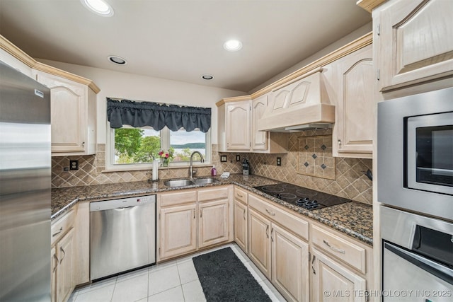kitchen with light tile patterned flooring, light brown cabinets, premium range hood, a sink, and stainless steel appliances